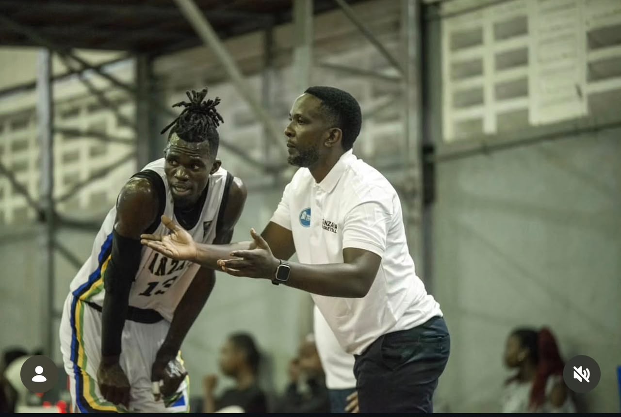 Coach Ashraf Harun Abdallah giving instructions beside a basketball player.