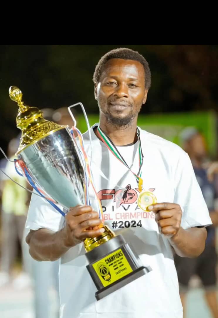 Basketball coach Barick Martin Kilimba holding a trophy.