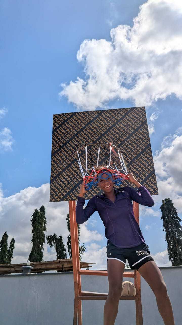A smiling young player beneath an outdoor basketball hoop.