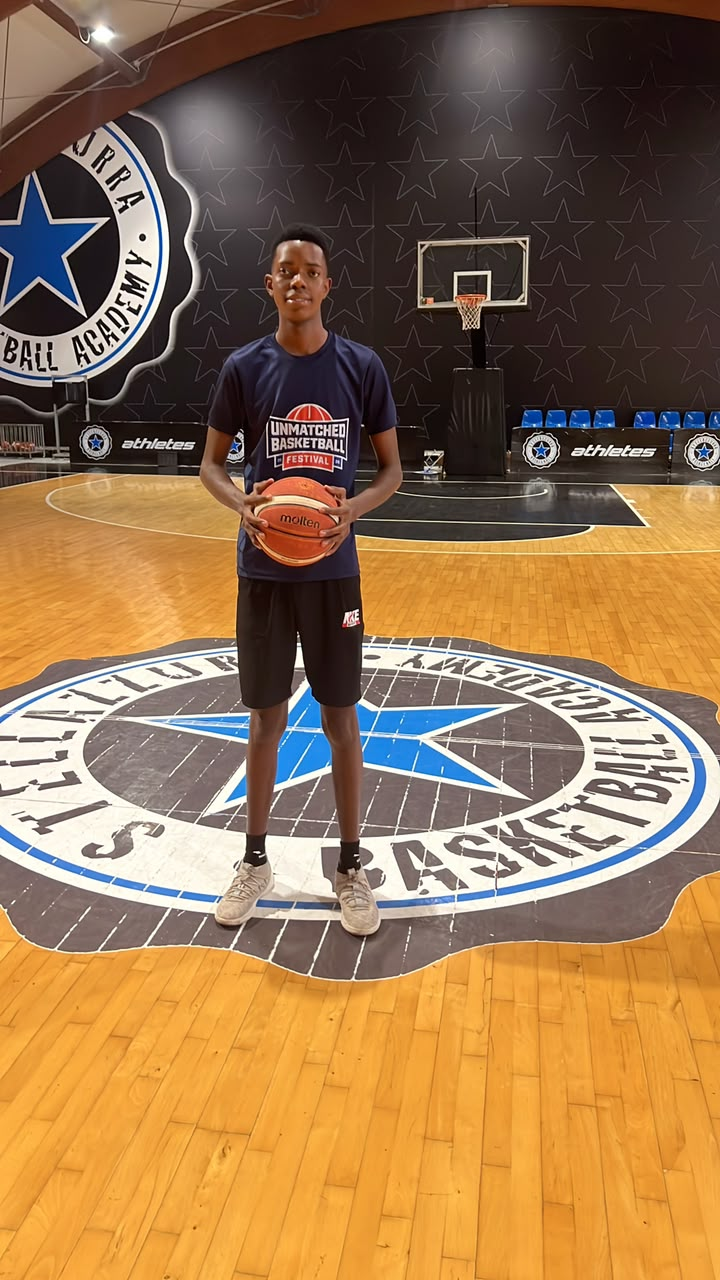 Isack R. Charles holding a basketball on the court at Stella Azzurra Basketball Academy.